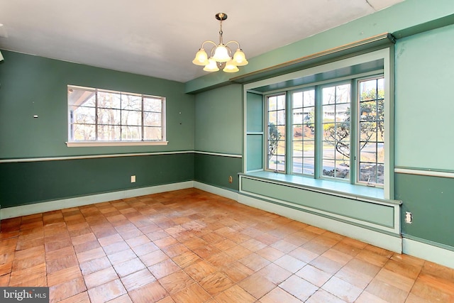 unfurnished room featuring a chandelier