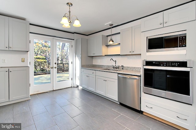 kitchen with stainless steel appliances, white cabinetry, sink, and decorative light fixtures