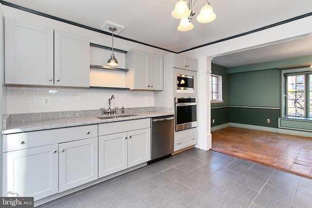 kitchen featuring white cabinetry, appliances with stainless steel finishes, sink, and decorative light fixtures