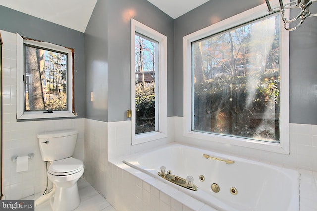 bathroom featuring a relaxing tiled tub, tile walls, and toilet