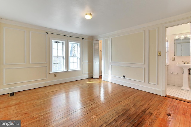 unfurnished bedroom with crown molding, ensuite bath, and light hardwood / wood-style flooring