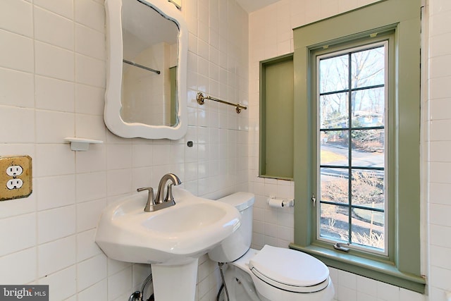 bathroom with a healthy amount of sunlight, tile walls, and toilet