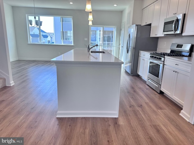 kitchen featuring stainless steel appliances, hanging light fixtures, and white cabinets