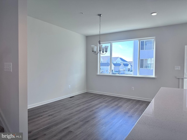 unfurnished dining area with dark wood-type flooring and a chandelier