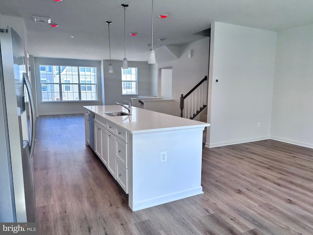 kitchen featuring sink, white cabinetry, a center island with sink, appliances with stainless steel finishes, and pendant lighting