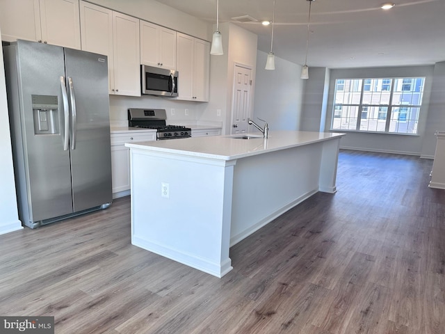 kitchen featuring sink, hanging light fixtures, stainless steel appliances, a kitchen island with sink, and white cabinets