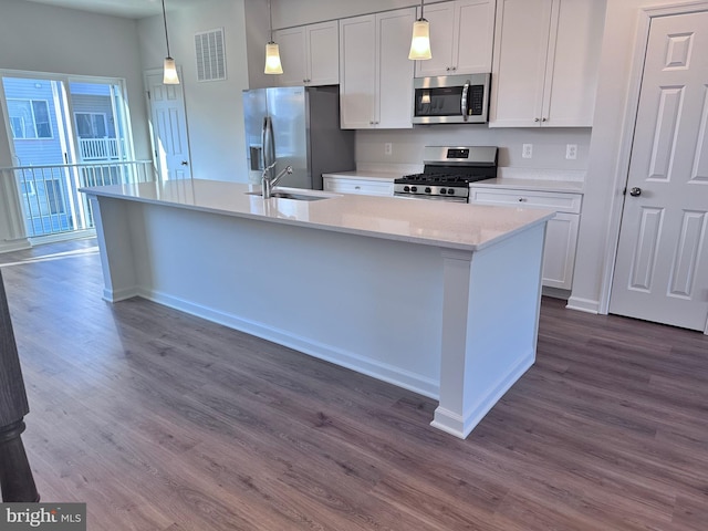 kitchen featuring stainless steel appliances, an island with sink, pendant lighting, and white cabinets