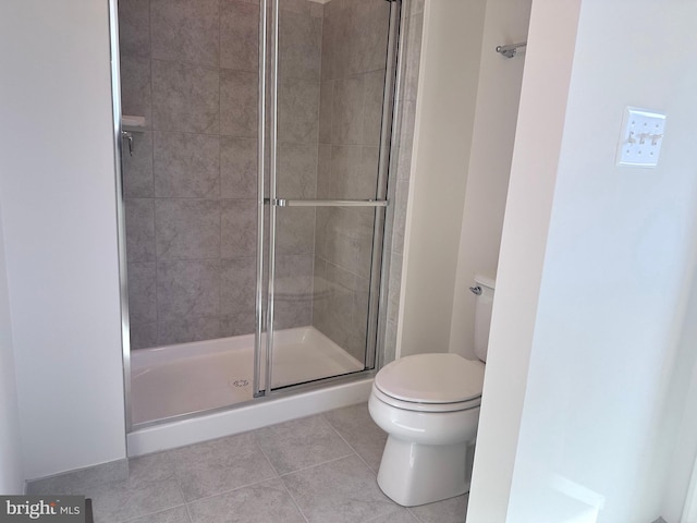 bathroom featuring a shower with door, tile patterned floors, and toilet