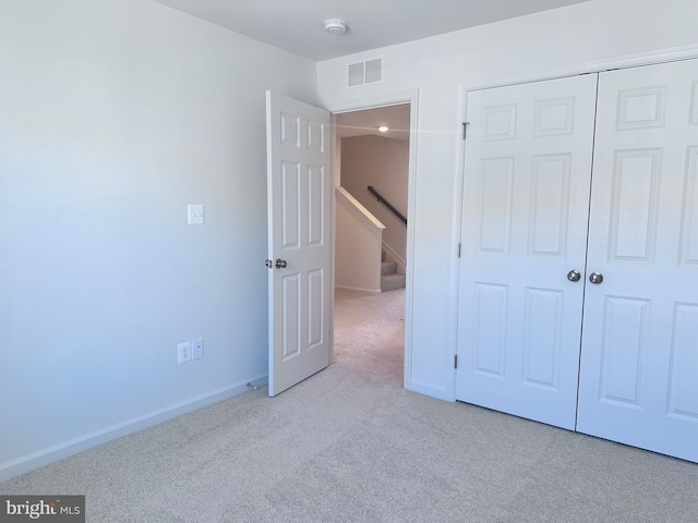 unfurnished bedroom featuring light colored carpet and a closet