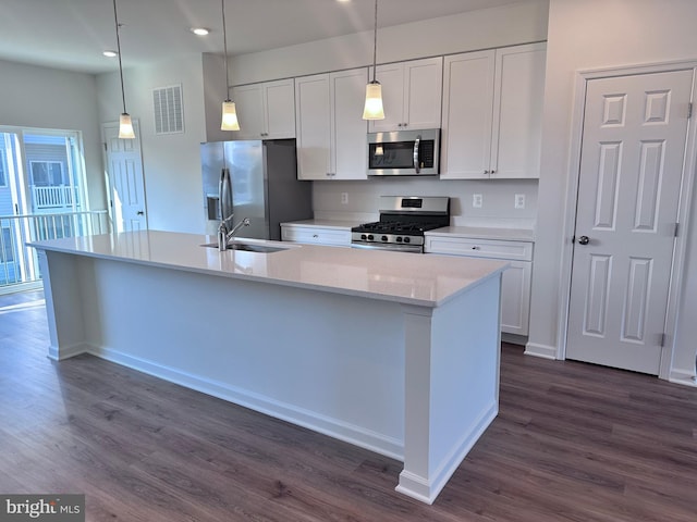 kitchen featuring sink, hanging light fixtures, a center island with sink, stainless steel appliances, and white cabinets