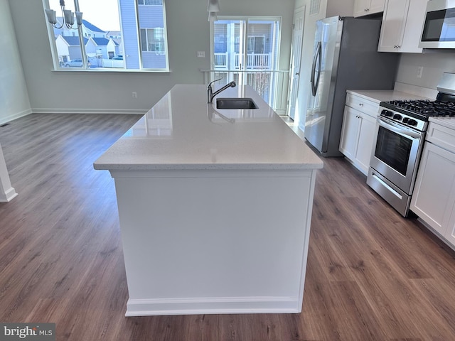 kitchen featuring white cabinetry, sink, light stone counters, stainless steel appliances, and a center island with sink