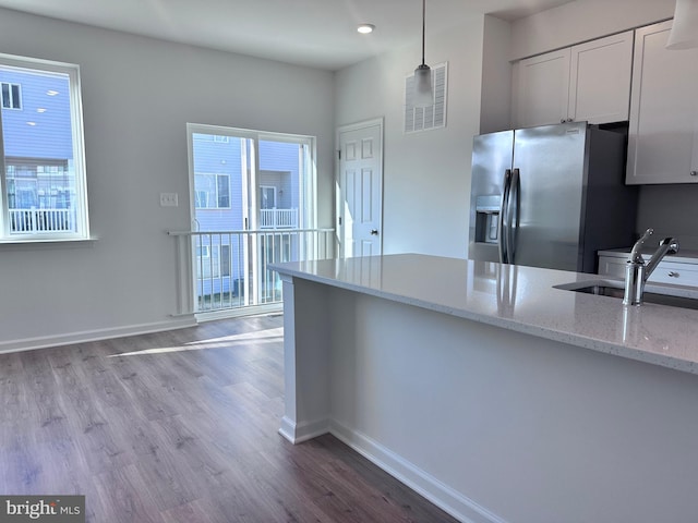 kitchen with pendant lighting, stainless steel fridge with ice dispenser, white cabinetry, and light stone countertops