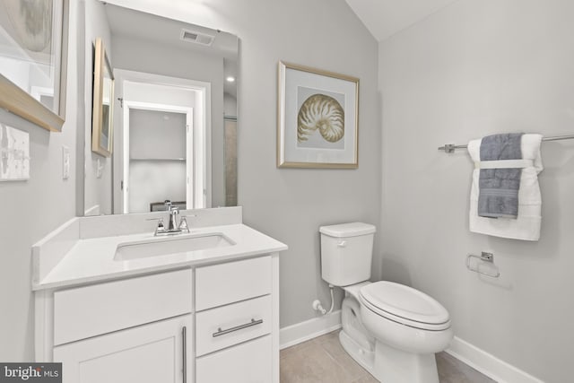 bathroom with tile patterned flooring, vanity, vaulted ceiling, and toilet