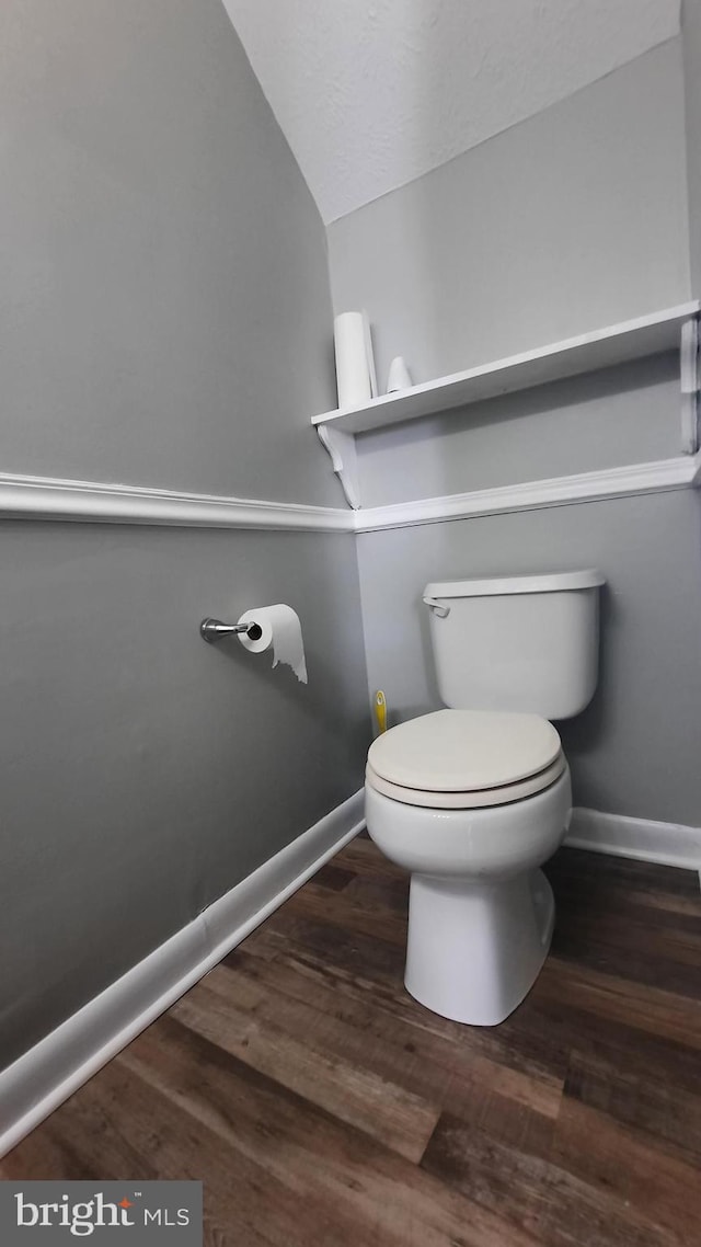 bathroom featuring hardwood / wood-style flooring, lofted ceiling, and toilet