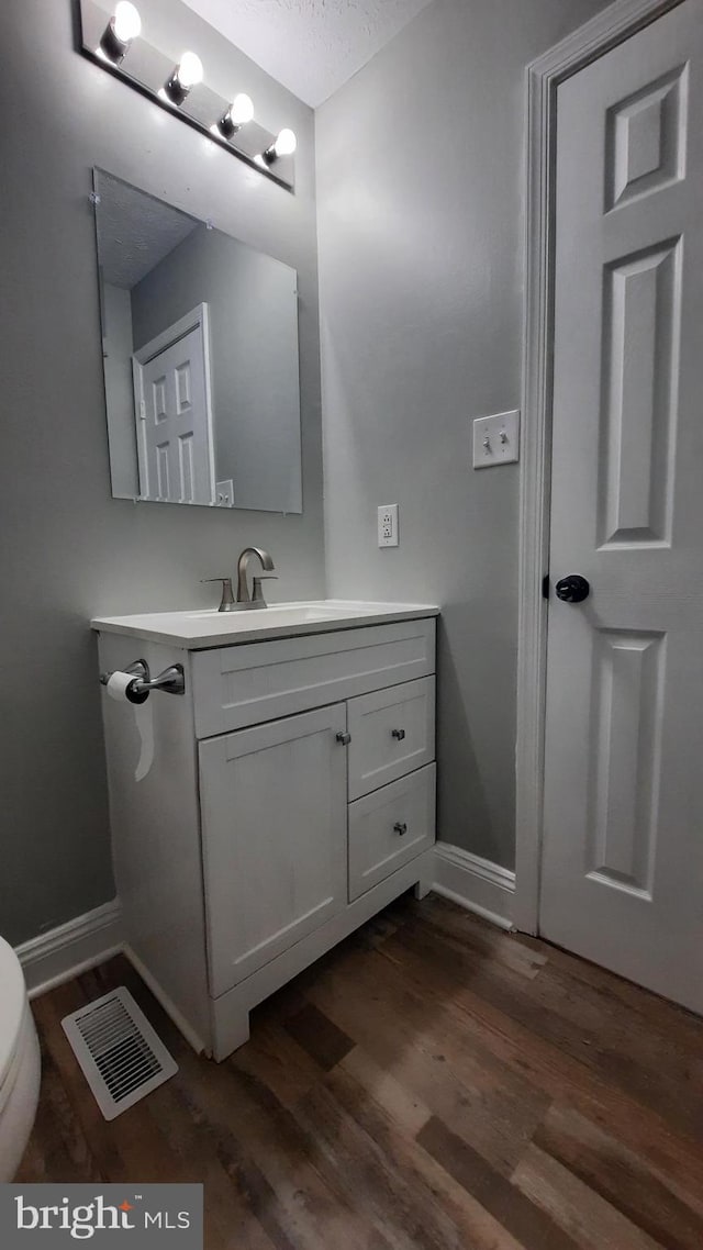 bathroom with wood-type flooring, toilet, and vanity