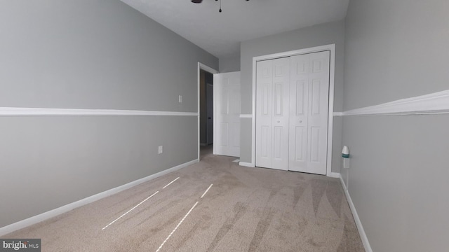 unfurnished bedroom featuring light colored carpet, a closet, and ceiling fan