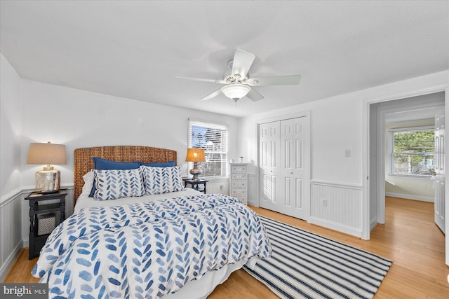 bedroom with ceiling fan, a closet, light hardwood / wood-style floors, and multiple windows