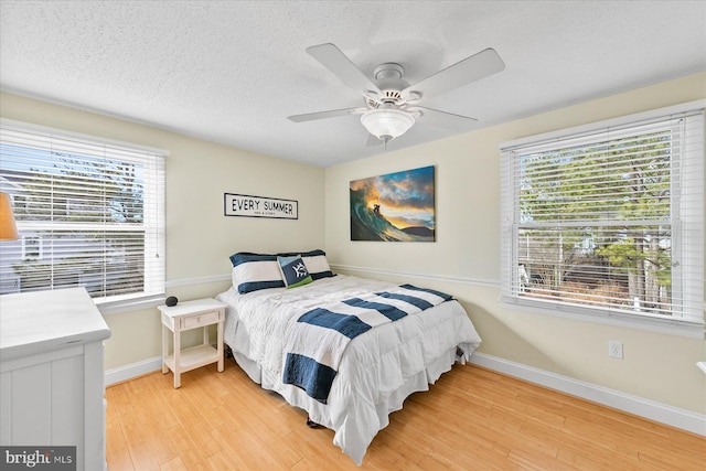 bedroom featuring hardwood / wood-style flooring, ceiling fan, a textured ceiling, and multiple windows