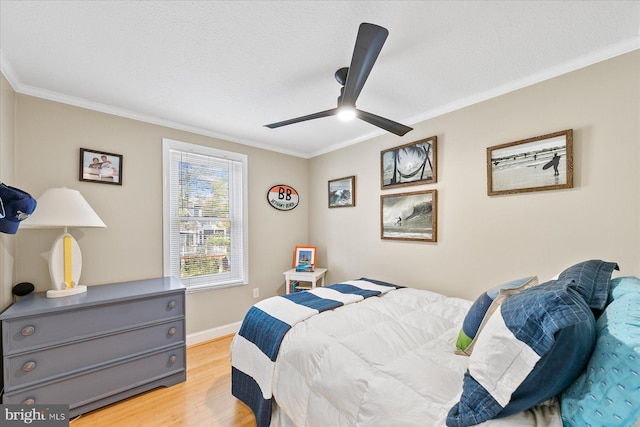 bedroom featuring ornamental molding, ceiling fan, a textured ceiling, and light hardwood / wood-style floors