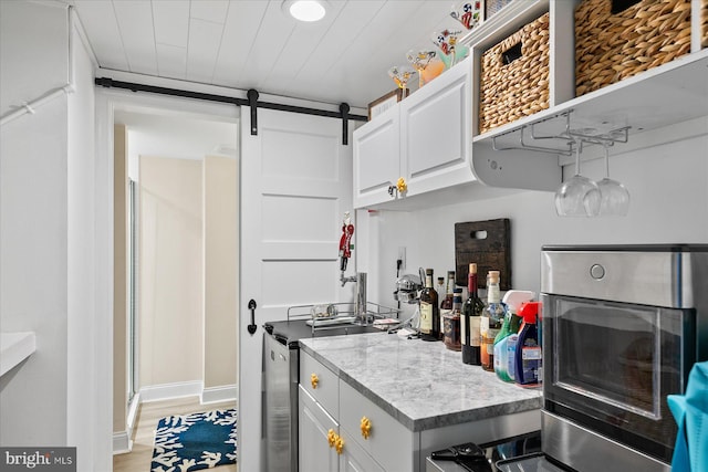 kitchen featuring a barn door, light hardwood / wood-style floors, and white cabinets