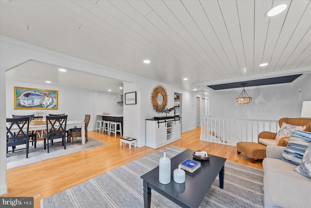 living room featuring crown molding, a chandelier, and light hardwood / wood-style floors