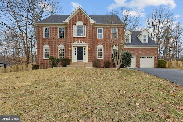 colonial inspired home with a garage and a front lawn