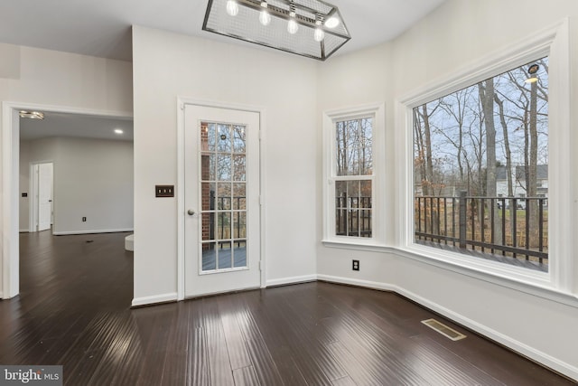 unfurnished dining area with dark wood-type flooring