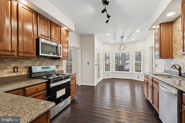 kitchen featuring sink, stone counters, hanging light fixtures, stainless steel appliances, and dark hardwood / wood-style floors