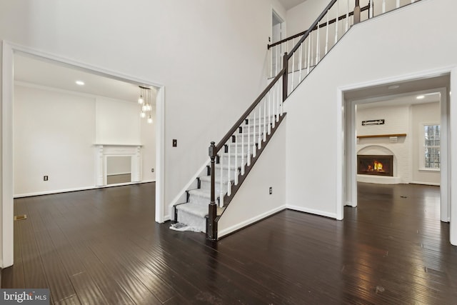 stairs featuring a brick fireplace, hardwood / wood-style flooring, and a high ceiling