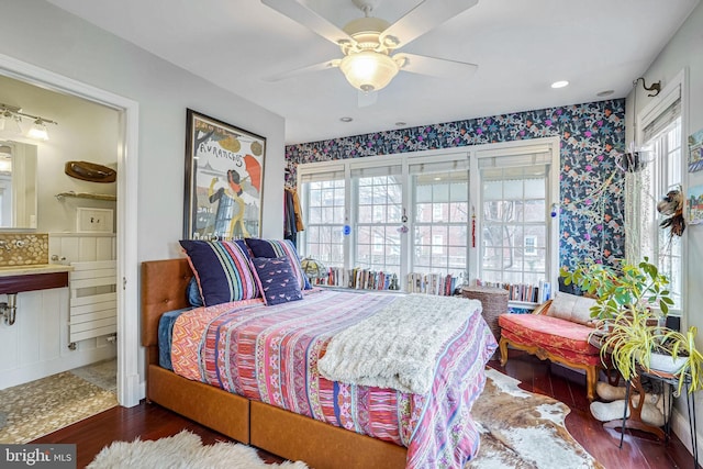 bedroom featuring connected bathroom, dark wood-type flooring, and ceiling fan