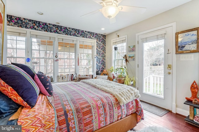 bedroom featuring multiple windows, hardwood / wood-style floors, access to outside, and ceiling fan