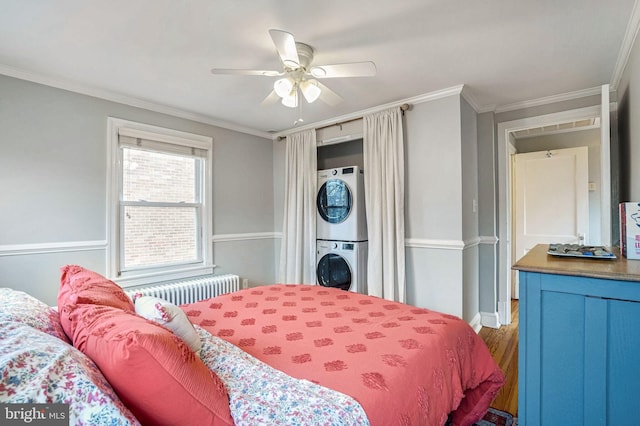 bedroom with crown molding, radiator heating unit, wood-type flooring, and stacked washing maching and dryer