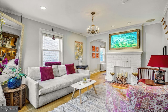 living room with an inviting chandelier, ornamental molding, radiator heating unit, a fireplace, and light hardwood / wood-style floors