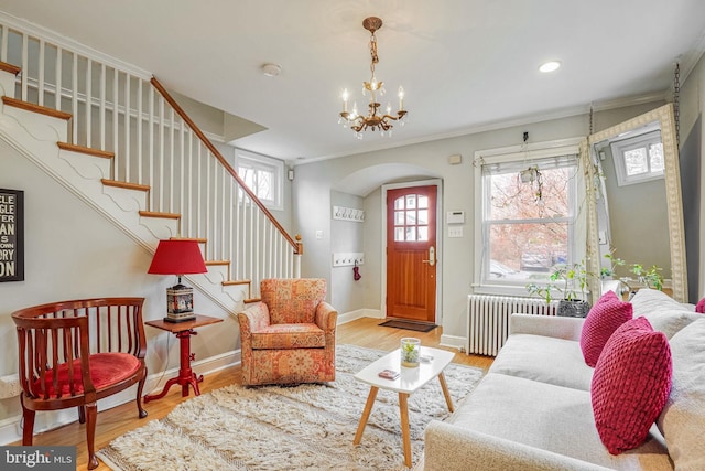 interior space with a notable chandelier, crown molding, radiator heating unit, and light hardwood / wood-style floors