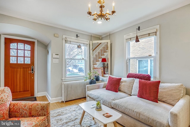 living room featuring crown molding, radiator heating unit, a notable chandelier, and light wood-type flooring