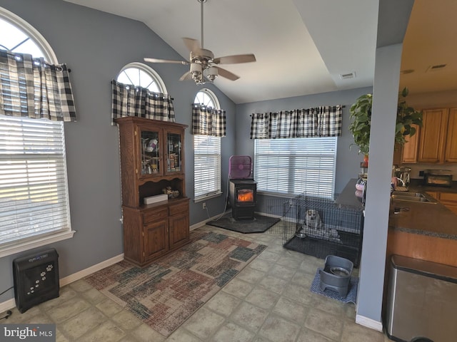 interior space with a wood stove, plenty of natural light, ceiling fan, and lofted ceiling