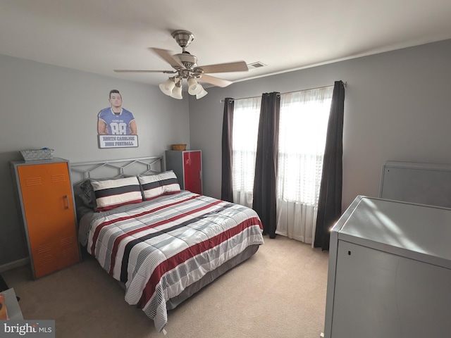 bedroom with visible vents, ceiling fan, and light carpet