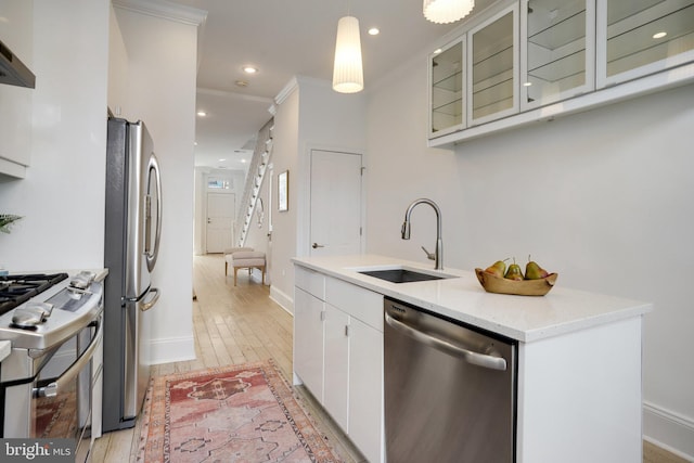 kitchen featuring stainless steel appliances, light stone counters, white cabinets, pendant lighting, and sink