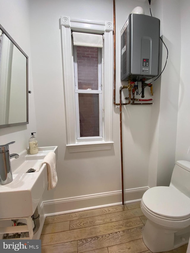 bathroom featuring sink, toilet, water heater, and wood-type flooring