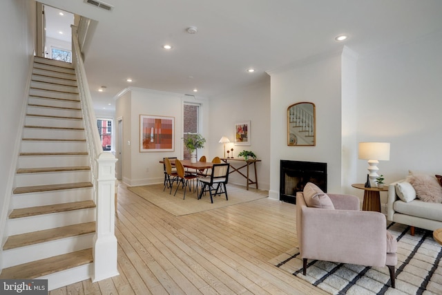 living room with ornamental molding and light hardwood / wood-style floors