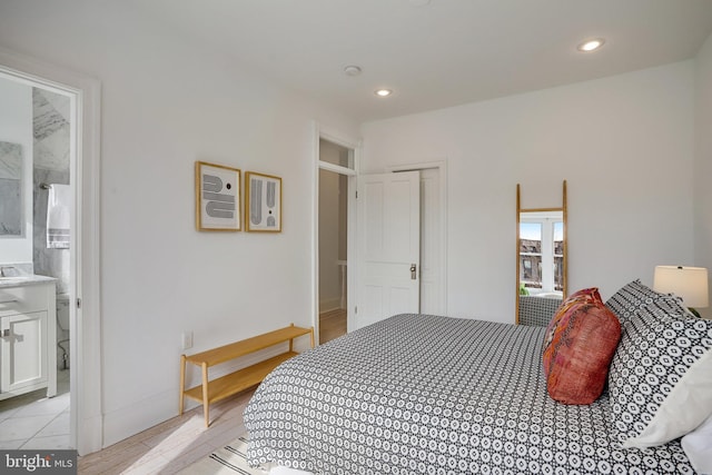 bedroom with light hardwood / wood-style floors, ensuite bath, and a closet