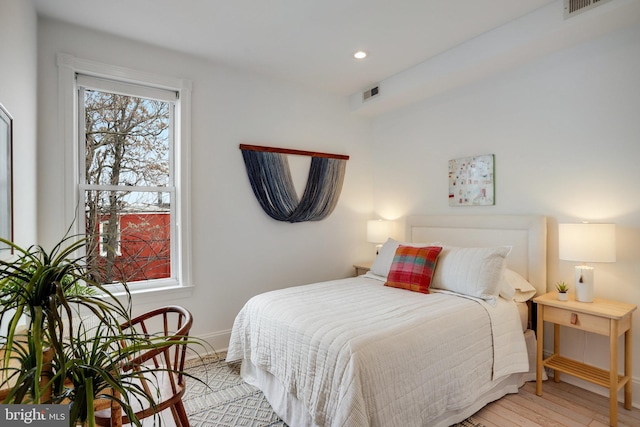 bedroom with multiple windows and light hardwood / wood-style flooring