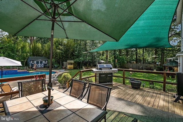 deck featuring grilling area, a storage shed, and a lawn