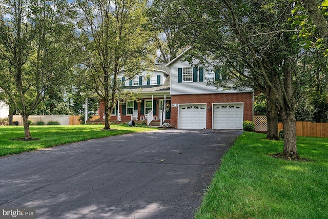 view of property featuring a garage, a porch, and a front lawn