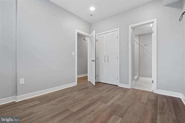 unfurnished bedroom with connected bathroom and light hardwood / wood-style flooring