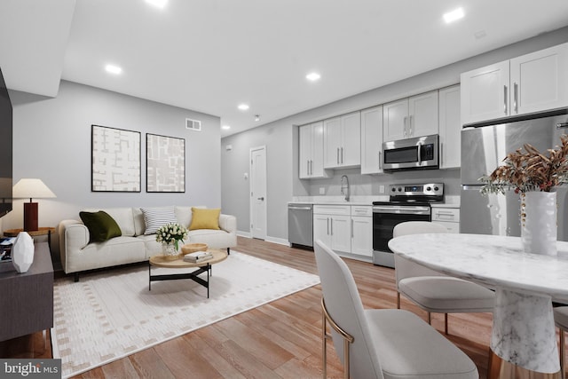 kitchen featuring white cabinetry, stainless steel appliances, and light hardwood / wood-style floors