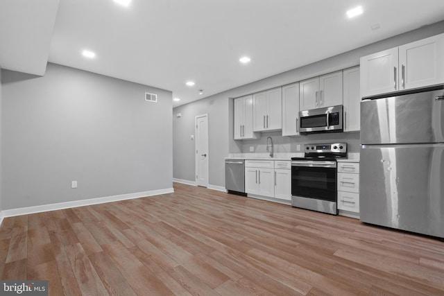 kitchen featuring sink, stainless steel appliances, white cabinets, and light wood-type flooring