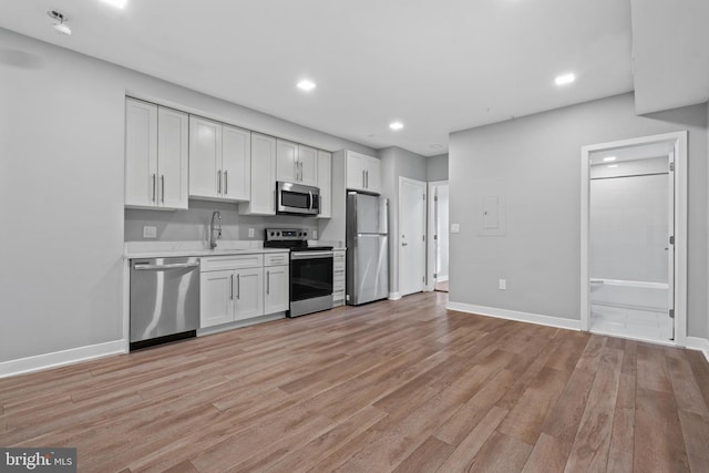 kitchen with white cabinetry, sink, stainless steel appliances, and light hardwood / wood-style floors