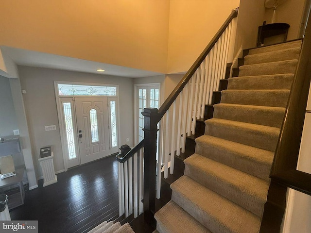 entryway featuring dark hardwood / wood-style flooring and a towering ceiling