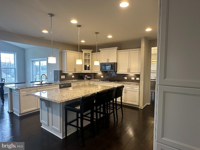 kitchen with a kitchen bar, sink, white cabinetry, a kitchen island, and black appliances